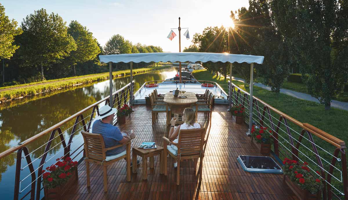 elderly couple relaxing on the top deck of a river cruise boat in france