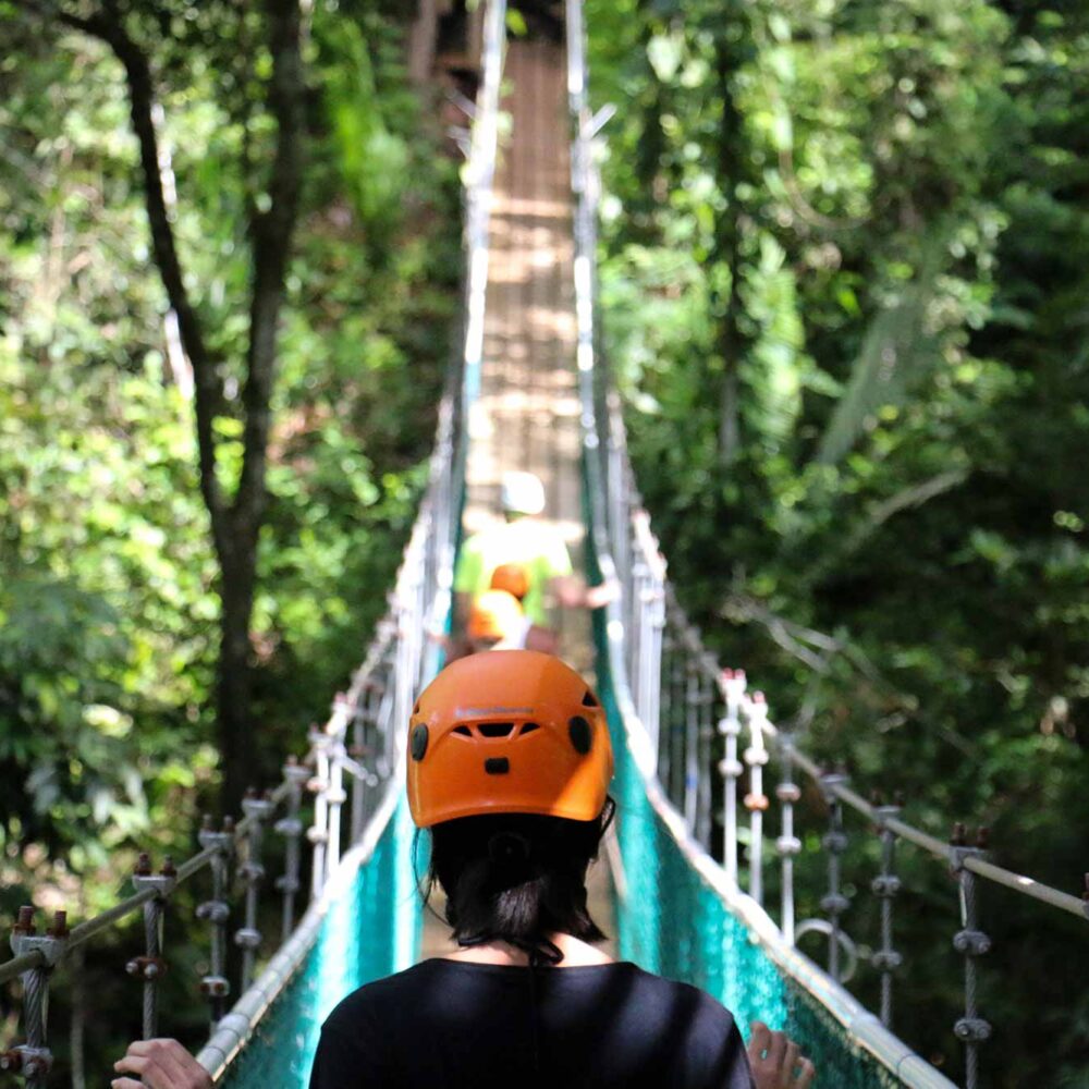 hikers walking on a suspension bridge in a jungle in belize