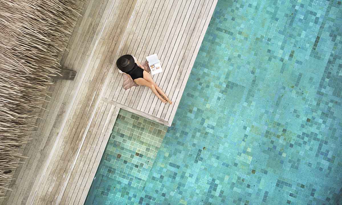 Six-Senses-Fiji woman reading a newspaper by the pool