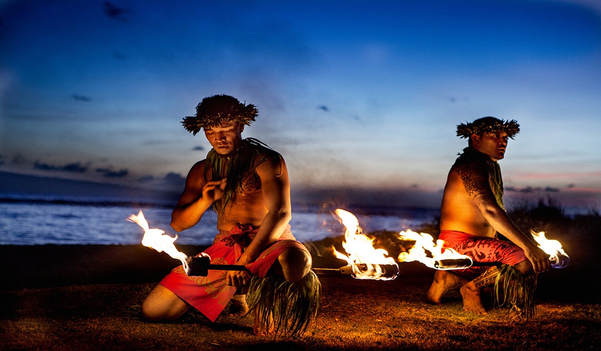 Hawaiian dancers fire dancing in front of blue sunset